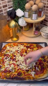 Slicing a hot, freshly baked tray of Turkish-style pizza into serving squares.