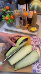 Slicing zebra-peeled globe eggplants into thick rounds for the casserole.