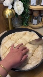 Slicing the assembled raw cheese börek into squares before frying.