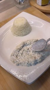 Spreading a smooth layer of garlic yogurt eggplant base on a serving dish.