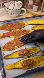 Spreading the spiced meat filling onto a roasted eggplant slice.