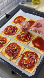 Spreading a thin layer of the prepared tomato sauce onto the center of each puff pastry piece.