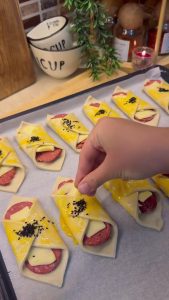 Sprinkling black nigella seeds over the glazed puff pastry bites.
