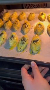 Sprinkling black cumin (nigella) seeds over the egg-washed pastries before baking