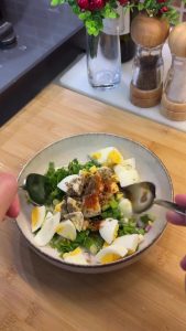 Squeezing a half lemon over the egg salad for a zesty and tangy dressing.