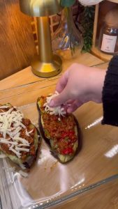 Creating a three-layer stack of eggplant, meat sauce, and grated cheese.
