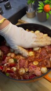 Stirring salt, pepper, and oregano into the meat and vegetable mixture.