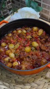 Removing the steaming, golden-brown Belen Tava from the oven.