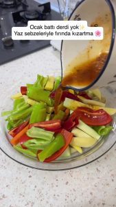Tossing mixed summer vegetables in a large bowl with the garlic and herb oil.