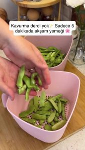 Trimming the ends and cutting fresh green beans in half on a wooden board.
