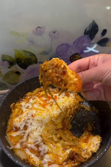 A pan of Turkish caramelized onion and eggs topped with melted cheese and red pepper flakes.