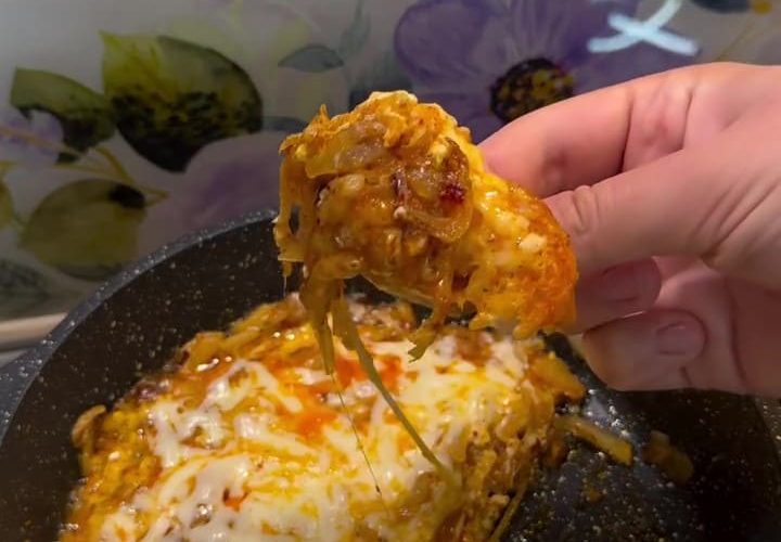 A pan of Turkish caramelized onion and eggs topped with melted cheese and red pepper flakes.