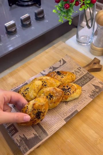 A tray of golden brown Turkish dill and cheese pastries sprinkled with black cumin seeds.