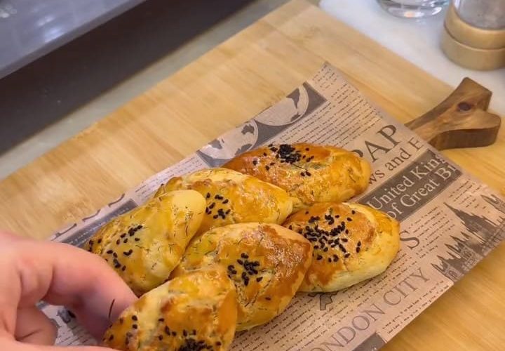 A tray of golden brown Turkish dill and cheese pastries sprinkled with black cumin seeds.