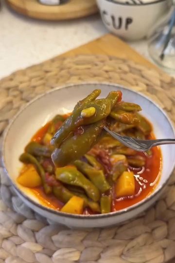 A traditional plate of Turkish green beans in olive oil sauce with potatoes and tomatoes.