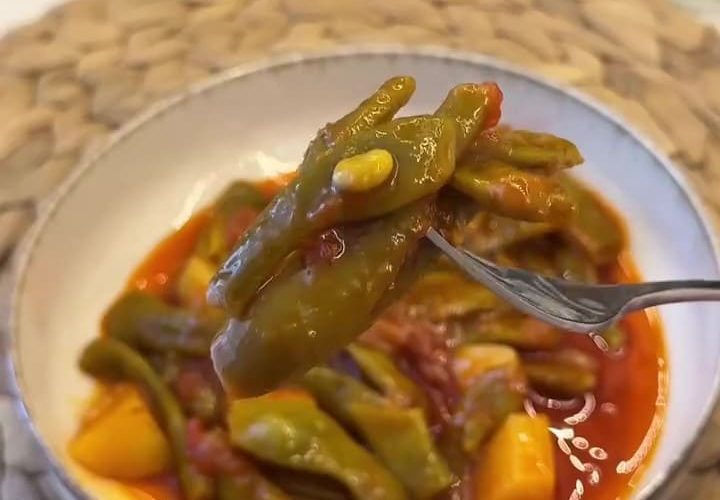 A traditional plate of Turkish green beans in olive oil sauce with potatoes and tomatoes.