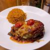 A golden-brown layered globe eggplant casserole with melted cheese and tomato slices