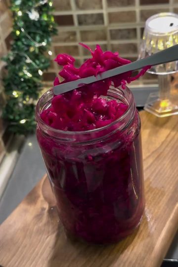 A glass jar filled with bright pink-purple pickled Turkish red cabbage.