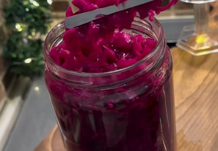 A glass jar filled with bright pink-purple pickled Turkish red cabbage.