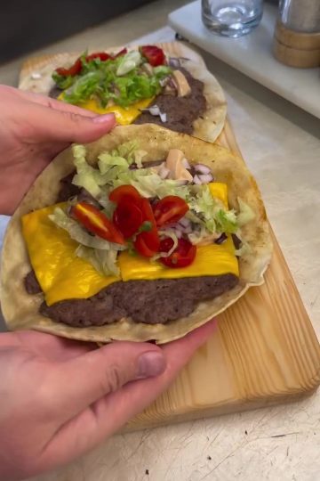A delicious viral smash taco burger with melted cheddar cheese, lettuce, and sauce.