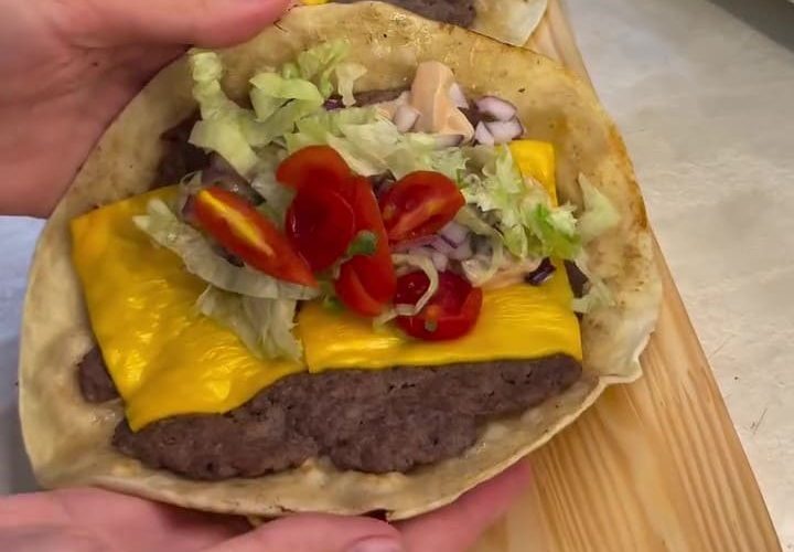 A delicious viral smash taco burger with melted cheddar cheese, lettuce, and sauce.