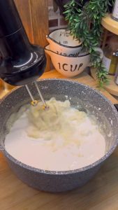 Whisking cold heavy cream into the cooled pudding base with an electric mixer.