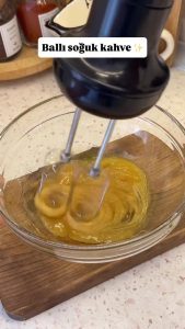 Whipping raw honey in a bowl until it changes color and becomes thick and creamy.