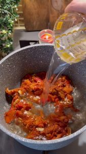 Whisking cold water into the roasted pepper mixture to prevent lumps.
