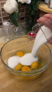 Whisking eggs and sugar in a glass bowl until the mixture is light and foamy.