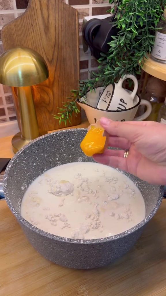 Whisking milk, flour, starch, and egg yolk in a pot for the pudding base.