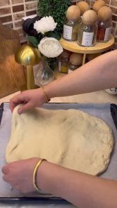 Whisking tomato paste, oil, and dried oregano with water for the pizza base.