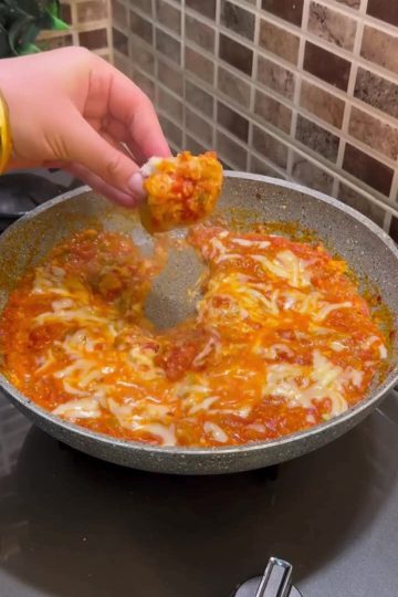 A steaming pan of creamy Çakallı menemen with melted cheese and fresh bread.