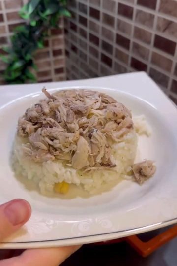 A plate of fluffy Turkish rice topped with shredded chicken, chickpeas, and black pepper.