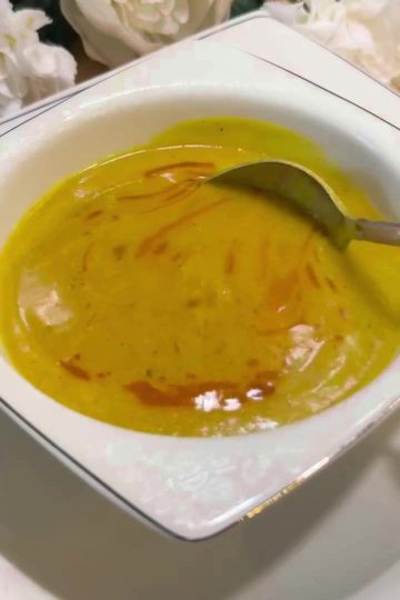 A bowl of golden Turkish lentil soup with a paprika butter drizzle and lemon.