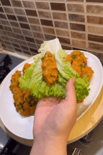 A beautiful arrangement of red lentil balls on a bed of lettuce with lemon wedges.