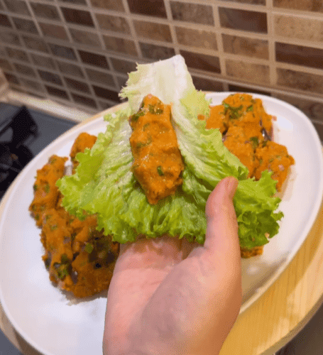 A beautiful arrangement of red lentil balls on a bed of lettuce with lemon wedges.