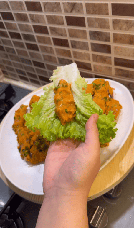 A beautiful arrangement of red lentil balls on a bed of lettuce with lemon wedges.