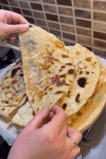 A stack of buttered Turkish spinach gözlemes on a wooden board.