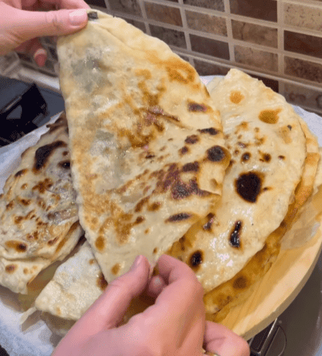 A stack of buttered Turkish spinach gözlemes on a wooden board.