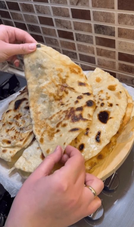A stack of buttered Turkish spinach gözlemes on a wooden board.
