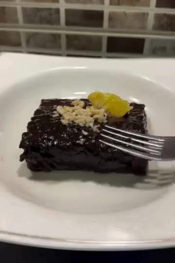 A slice of moist Turkish wet chocolate cake topped with ground pistachios.