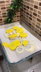 Layering sliced onions and potatoes in a baking dish.