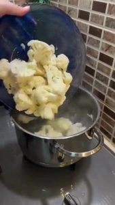 Boiling fresh cauliflower florets in a large pot.