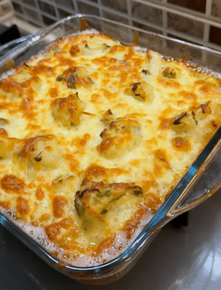 A golden-brown cheesy cauliflower gratin served in a glass baking dish.