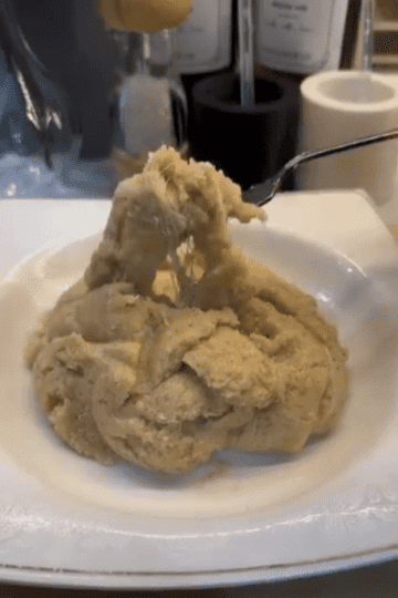 A spoonful of golden semolina halva with long, stretchy melted cheese strands.