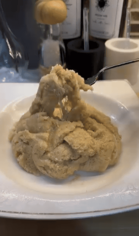 A spoonful of golden semolina halva with long, stretchy melted cheese strands.