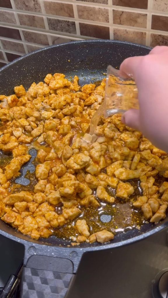 Adding a splash of water to the chicken and paprika oil mixture.
