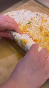 Rolling a finished chicken tantuni wrap tightly.