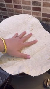 Pressing a fresh lavash bread onto the hot tantuni sauce.