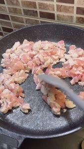 Sautéing diced chicken in a hot skillet until golden.